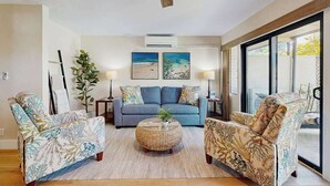 Ein Wohnzimmer mit einer Couch, zwei Sesseln, einem Couchtisch, einem Deckenventilator und zwei Bildern an der Wand.