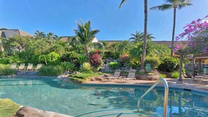 Ein Swimmingpool mit Liegestühlen, Palmen und blauem Himmel.