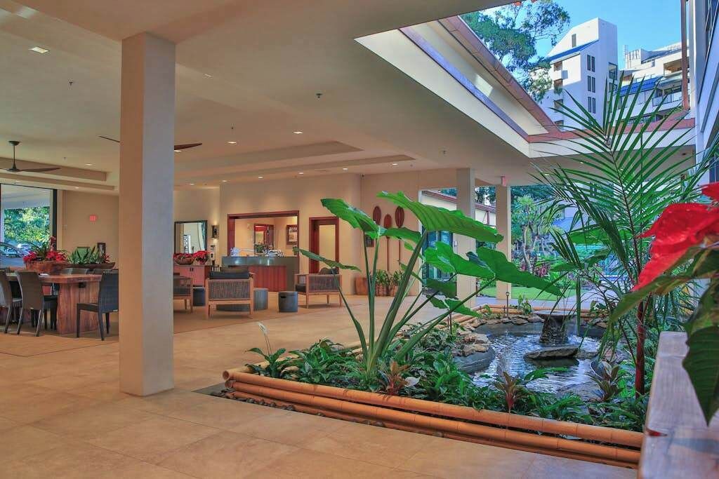 A hotel lobby with a reception desk, seating area, and a small indoor garden with a water feature.