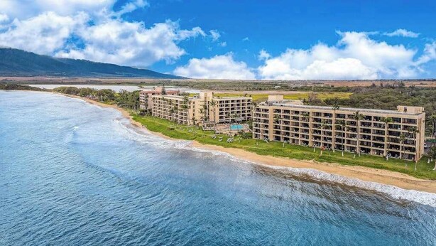 Um hotel à beira-mar com vários edifícios, uma praia e vista clara para o oceano.