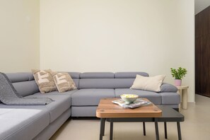 A modern living room with a grey sofa, a wooden coffee table with a bowl of popcorn, and a small side table with a plant. - Villa Casa Luta (Istria - Tinjan) (Tinjan)