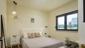 Ein Schlafzimmer mit Bett, Nachttisch und einem Fenster mit Blick.