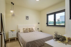 Ein Schlafzimmer mit Bett, Nachttisch und einem Fenster mit Blick.
