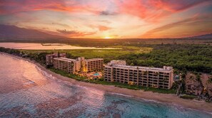 A beachfront hotel with multiple buildings, a pool, and a view of the ocean and sunset. - NEW Oceanfront Comfort for Four at Sugar Beach (Kihei)