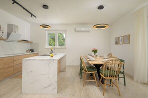Uma cozinha moderna com ilha de mármore, armários de madeira e iluminação pendente.
