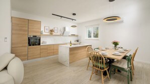 Cozinha moderna com ilha central, armários de madeira e área de refeições com cadeiras e mesa.