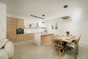 Eine moderne Küche mit einer zentralen Kochinsel, Holzschränken und einem Essbereich mit Stühlen und einem Tisch.