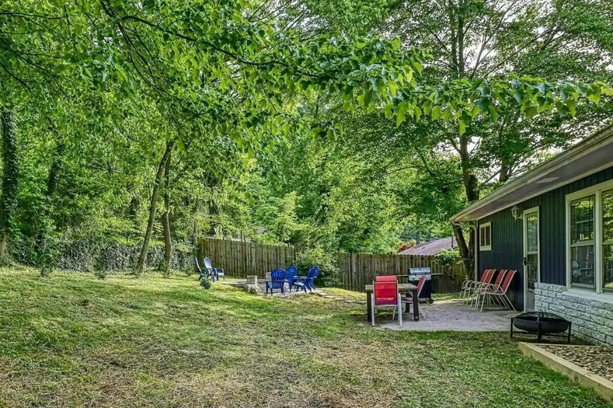 A backyard with a patio, outdoor seating, a barbecue grill, and a wooden fence.