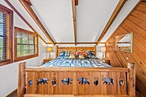A wooden bed with animal-themed headboard, a window with blinds, and a mirror on the wall. - Z - Little Bear Getaway (Sevierville)