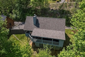 A two-story house with a balcony, surrounded by dense greenery. - Tiny Pines (Sevierville)