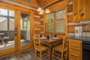A wooden interior with a dining table, chairs, and a kitchen area. - Tiny Pines (Sevierville)