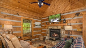 A log cabin interior with a fireplace, a television, and a cozy seating area. - Tiny Pines (Sevierville)