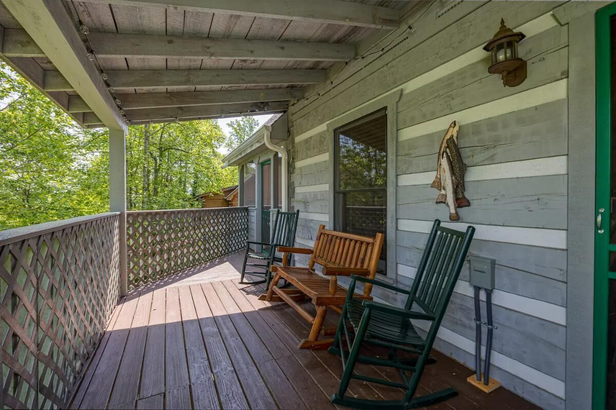 A wooden porch with a lattice railing, wooden benches, and a lantern.