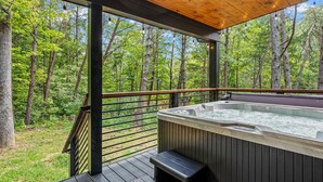 Ein Whirlpool auf einer Holzdielen-Terrasse mit Blick auf einen Wald.