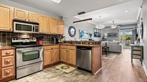 A modern kitchen with wooden cabinets, stainless steel appliances, and a dining area with a sofa and bar stools. - River Overlook (Sevierville)