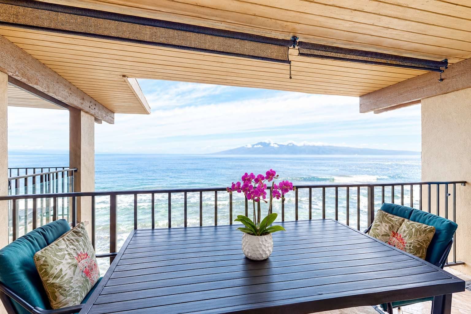 Een balkon met een tafel en stoelen, met uitzicht op de kust.