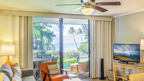 Ein Hotelzimmer mit einer Couch, Sesseln, einem Fernseher und Blick aufs Meer.