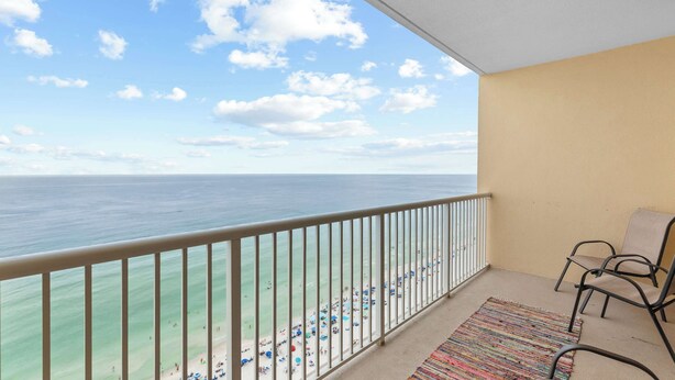 A balcony with a view of the ocean, a chair, and a colorful rug. - Majestic View Oceanfront (Panama City Beach)