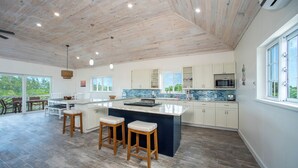 Cocina moderna con una isla grande, armarios blancos y vistas al exterior.