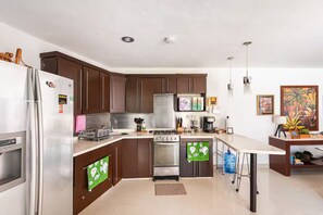 A modern kitchen with dark wooden cabinets, stainless steel appliances, and a central island. - A house with 2 bedrooms, 2 bathrooms, and a half-bath, featuring a large pool area! (Cancún)