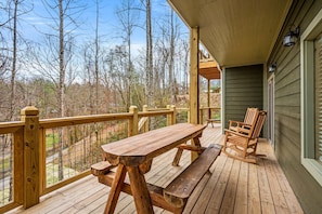 A wooden deck with a picnic table and chairs, overlooking a forested area. - Neverland (Gatlinburg)