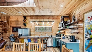 A wooden interior with a bar area, a dining table, and a kitchen counter. - Neverland (Gatlinburg)
