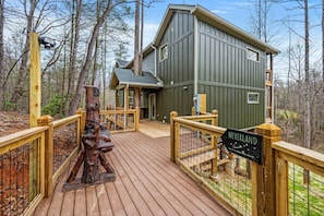 A wooden deck leading to a cabin with a 'NEVERLAND' sign, surrounded by trees. - Neverland (Gatlinburg)