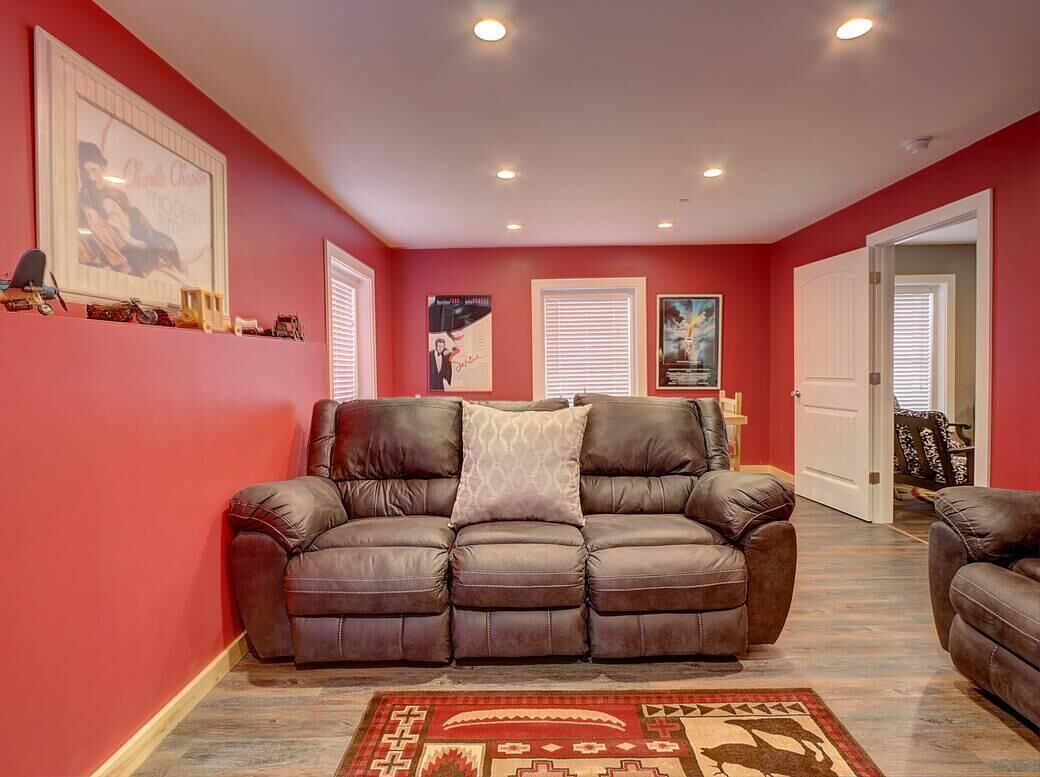 A living room with a brown leather sofa, a patterned rug, and a red wall.