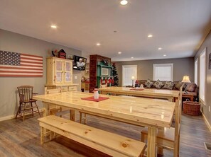 A dining area with wooden tables and benches, a large American flag on the wall, a Christmas tree, and a cozy seating area with a sofa and cushions. - A Family Tradition (Gatlinburg)