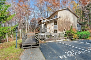 A two-story building with a stone facade, a balcony, and a parking area with a reserved sign. - Mountain Charm 2 (Gatlinburg)