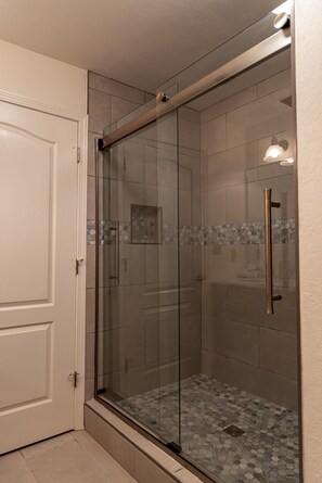 A glass-enclosed shower with a tiled floor and a white door. - Cozy Vista Condo (Pigeon Forge)