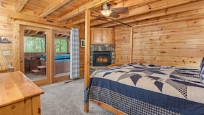 A wooden cabin interior with a bed, a fireplace, and a ceiling fan. - Fox n' Socks (Sevierville)