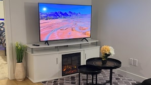 Una sala de estar moderna con una televisión de pantalla plana, chimenea, sofá y una mesa de centro.