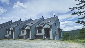 A large, multi-story building with a symmetrical facade, multiple chimneys, and a gravel driveway. - Enjoy stunning view in Waterville Estates! (Thornton)
