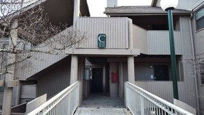 Un edificio con facciata in legno, un balcone con il cartello con la lettera 'C' e una scalinata che conduce all'ingresso.