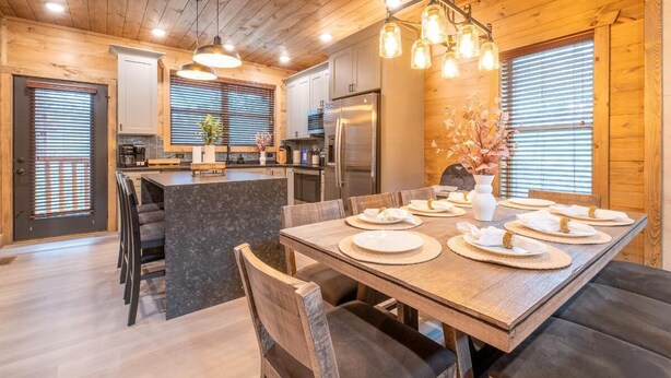 A wooden interior with a dining area, kitchen, and a large window with blinds. - Hillside Horizon (Sevierville)