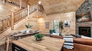 A wooden interior with a staircase, a fireplace, and a dining area. - Lykke Lodge (Pigeon Forge)