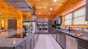 A modern kitchen with granite countertops, stainless steel appliances, and wooden ceiling. - Mayes Landing (Pigeon Forge)