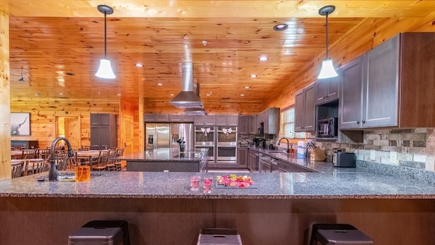 A spacious kitchen with wooden ceilings, granite countertops, and stainless steel appliances. - Mayes Landing (Pigeon Forge)
