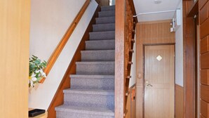 A carpeted staircase with wooden handrails and a door at the bottom. - Private whole-house stay in a quiet area of Shinoro, Sapporo. 3 bedrooms, up to 6 guests (札幌市)