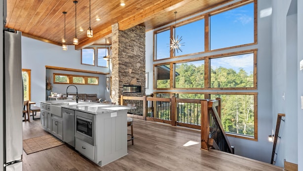 A spacious kitchen with a large island, wooden ceiling, and large windows offering a view of the outdoors. - Riverside Retreat in Ellijay GA (Ellijay)