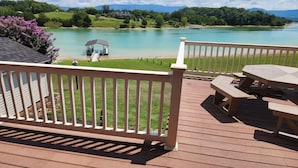 A deck with picnic tables overlooking a lake with a gazebo and grassy banks. - Three Horizons Retreat (Dandridge)