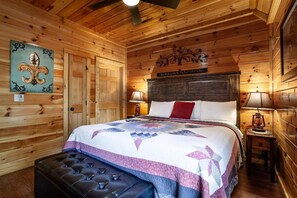 A wooden-paneled room with a bed, a bench, and a wall-mounted sign. - Poolin' Around (Pigeon Forge)