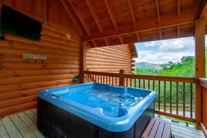 A wooden cabin with a hot tub on a deck. - Poolin' Around (Pigeon Forge)