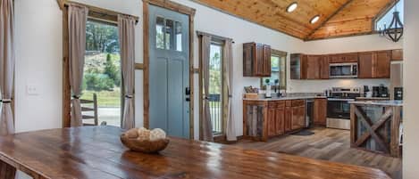 Una cocina amplia con alacenas de madera, una gran mesa de madera y vistas al exterior.