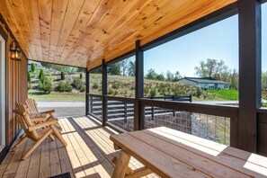 Um deck de madeira com bancos e vista para uma casa e paisagem.