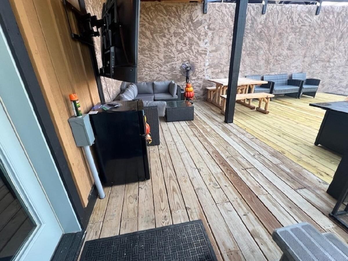 Eine Holzterrasse mit Gartenmöbeln, darunter eine Sitzecke mit Sofa und Tischen.