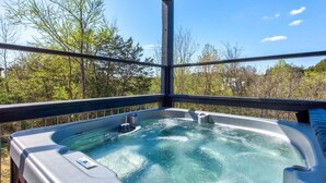 Ein Whirlpool mit Holzboden und Metallgeländern, umgeben von Bäumen.