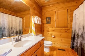 A wooden cabin bathroom with a sink, toilet, and shower curtain. - Z - The Overlook (Sevierville)