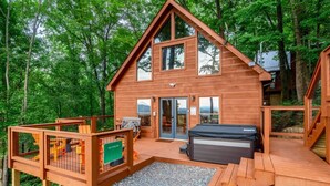 Een houten chalet met een terras, een hottub en een overdekte patio.